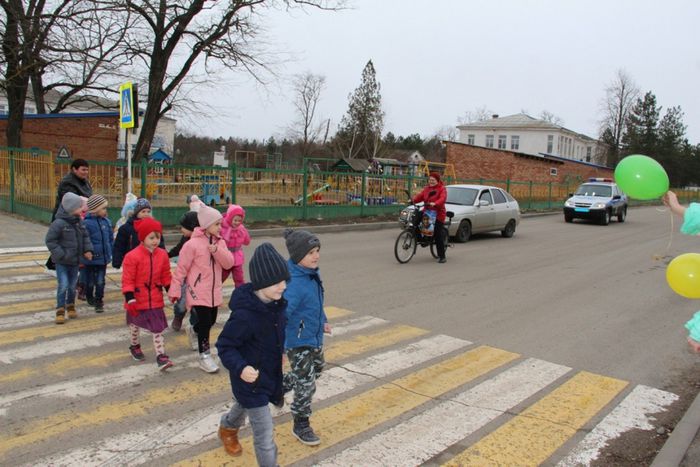 Фотография ребят из школьного отряда «Юные инспекторы дороги» СОШ № 1 переводят через дорогу своих подшефных дошколят, учащихся объединения «Всезнайка».